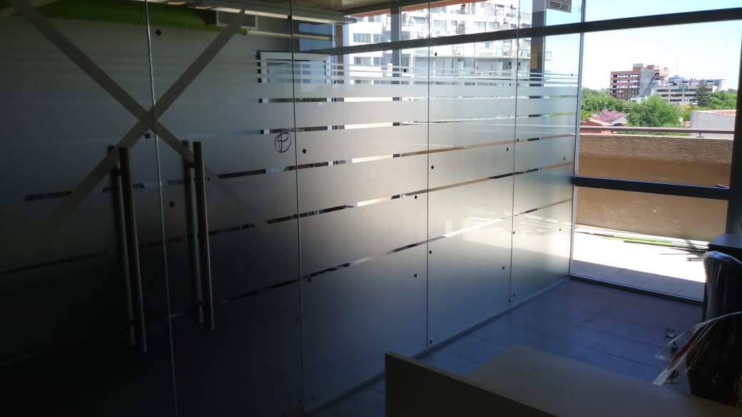 Divisiones de vidrio de una oficina con franjas de vinilo esmerilado y puertas de vidrio con manijas largas